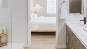 Een moderne badkamer met een douchecabine van glas, een witte wastafel en een houten wastafelmeubel.