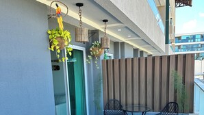 Moderni ulkobalconi, jossa on laatoitettu uima-allas, puulattia ja oleskelualue, jossa on tuoleja ja pöytä.