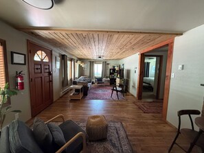 A spacious living area with a wooden ceiling, a sofa, a coffee table, and a rug. - Charming Miller Cabin in McCall! Sauna, utilities, snow removal, pet friendly! (McCall)