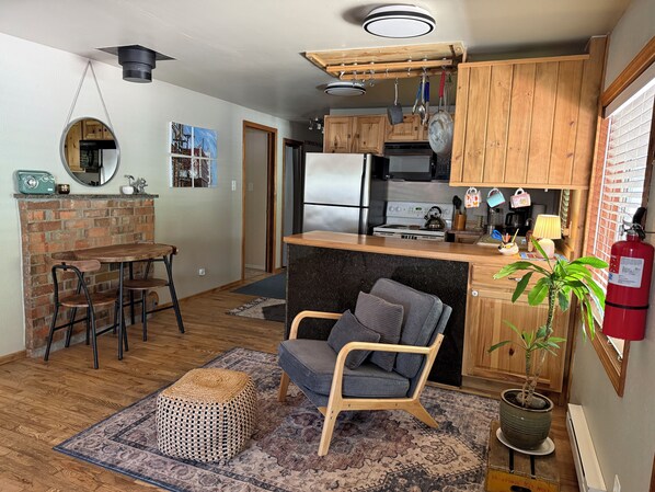 A compact kitchen with wooden cabinets, a built-in stove, and a hanging pot rack.