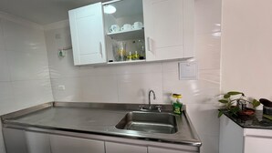A kitchen with a stainless steel sink, white cabinets, and a small countertop with a plant. - Sea view and historical center (with swimming pool and in front of the beach in Marbella) (Cartagena de Indias)