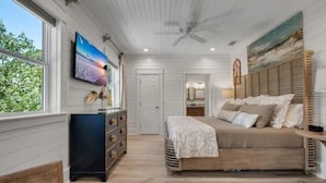 Quarto com cama, penteadeira e obra de arte na parede.