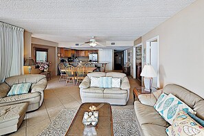 A living room with a sofa, armchairs, a coffee table, and a dining area with a table and chairs. - Corner 3BR w/ Gulf Views: Suntide III - Unit 1010 (South Padre Island)