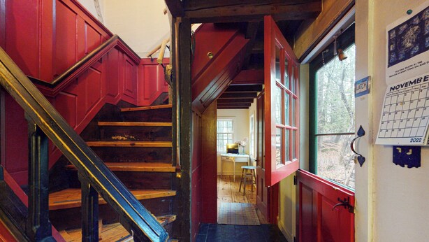 Una escalera con barandas rojas y negras que lleva a una habitación con una ventana y un calendario en la pared.