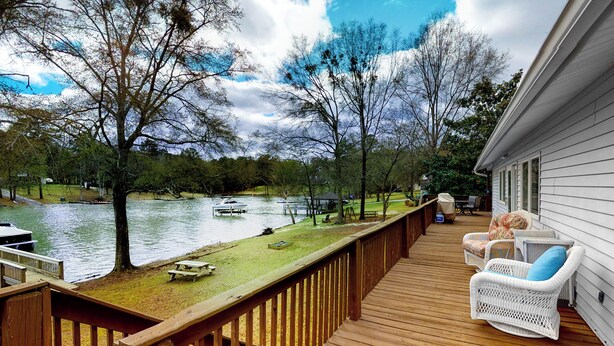 Una terrazza in legno con mobili in vimini che si affaccia su un lago.