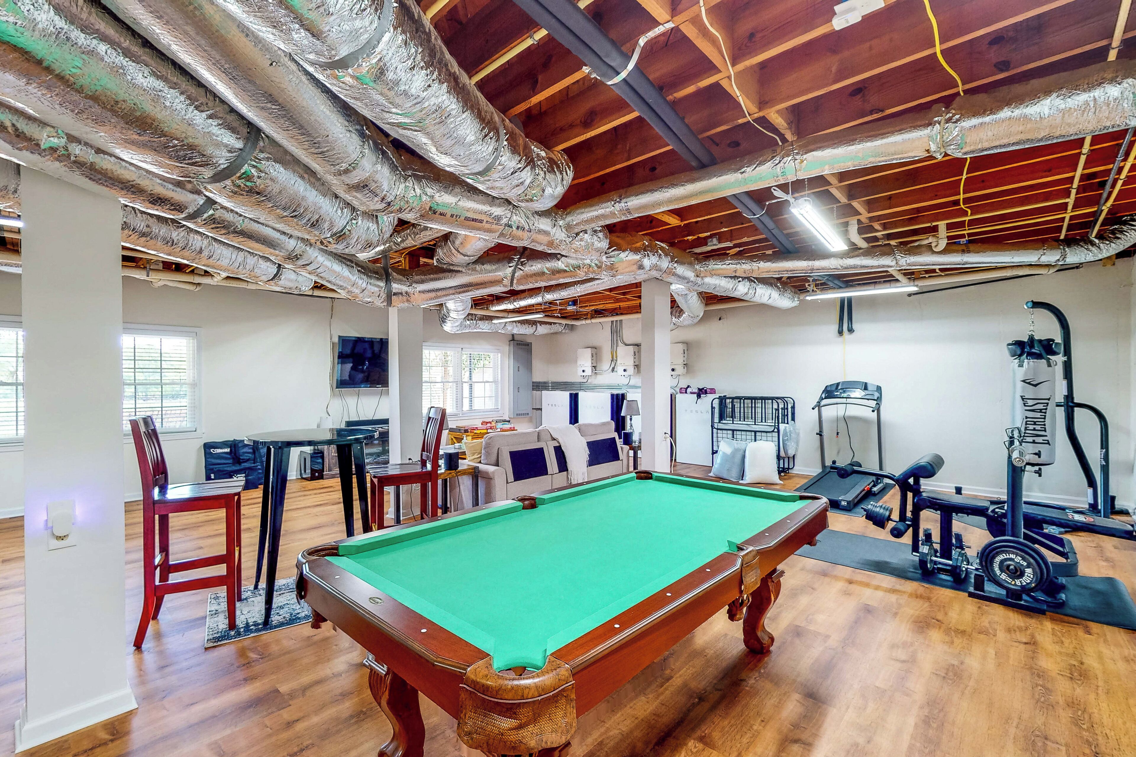 Une pièce spacieuse équipée d’une table de billard, d’appareils de musculation et d’un coin repas.