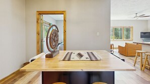 Ein geräumiger Raum mit einem Holztisch, einem gemusterten Teppich und einer großen Holztür zu einem weiteren Bereich.