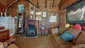 Ein rustikales Blockhaus-Interieur mit Holzbalkendecke, Kamin, einer Couch und einem Essbereich.