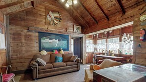 Ein rustikales Holzinterieur mit einer Couch, einer Holzkiste und einem Gemälde einer Meerjungfrau.