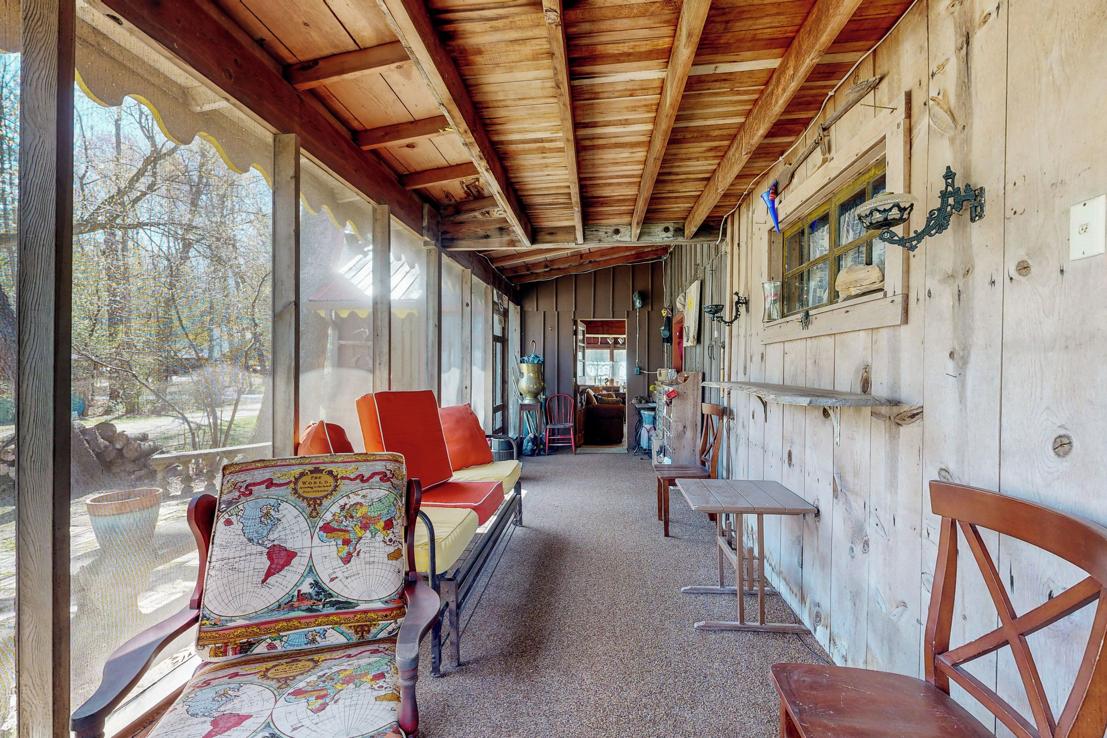 A wooden interior with a sofa, chairs, a table, and a map on a wall.