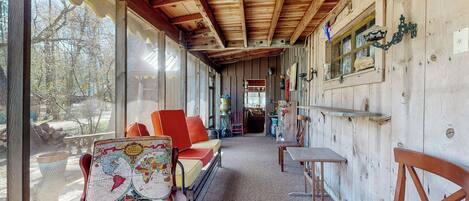 A wooden interior with a sofa, chairs, a table, and a map on a wall.