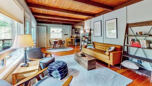 Un salón acogedor con techo de madera, un sofá, una mesa de centro y una estantería.