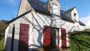 A two-story house with a steep roof, a small tower-like structure, and a window with shutters. - Maisonnette 4 personnes proche de la plage - WIFI (SARZEAU)