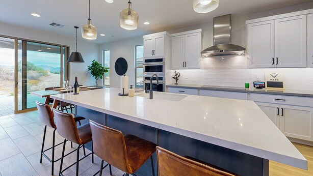 A modern kitchen with a large island, bar stools, stainless steel appliances, and a view through the glass door. - Mtn-View Patio & Resort Perks: Verde River Retreat (Rio Verde)