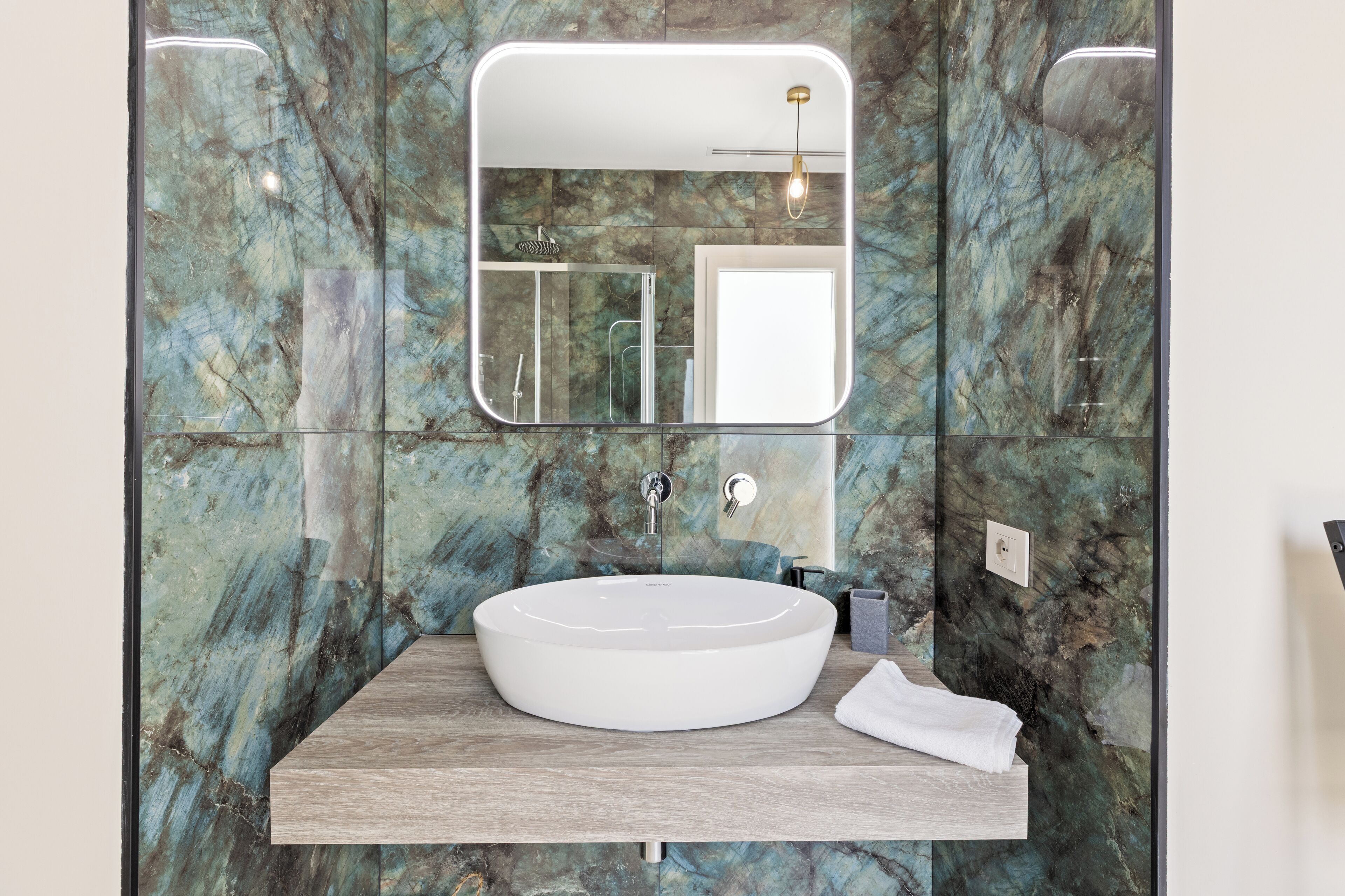 Un bany amb un gran vàter oval, un mirall i una cabina de dutxa.