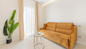 Ein modernes Wohnzimmer mit einer Couch, einem runden Beistelltisch und einer großen Pflanze.