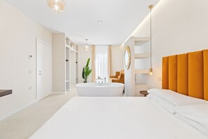 A modern hotel room with a large bed, a bathtub, a vanity with a mirror, and a plant. - Our Suite is designed to make each guest feel truly special (Iglesias)