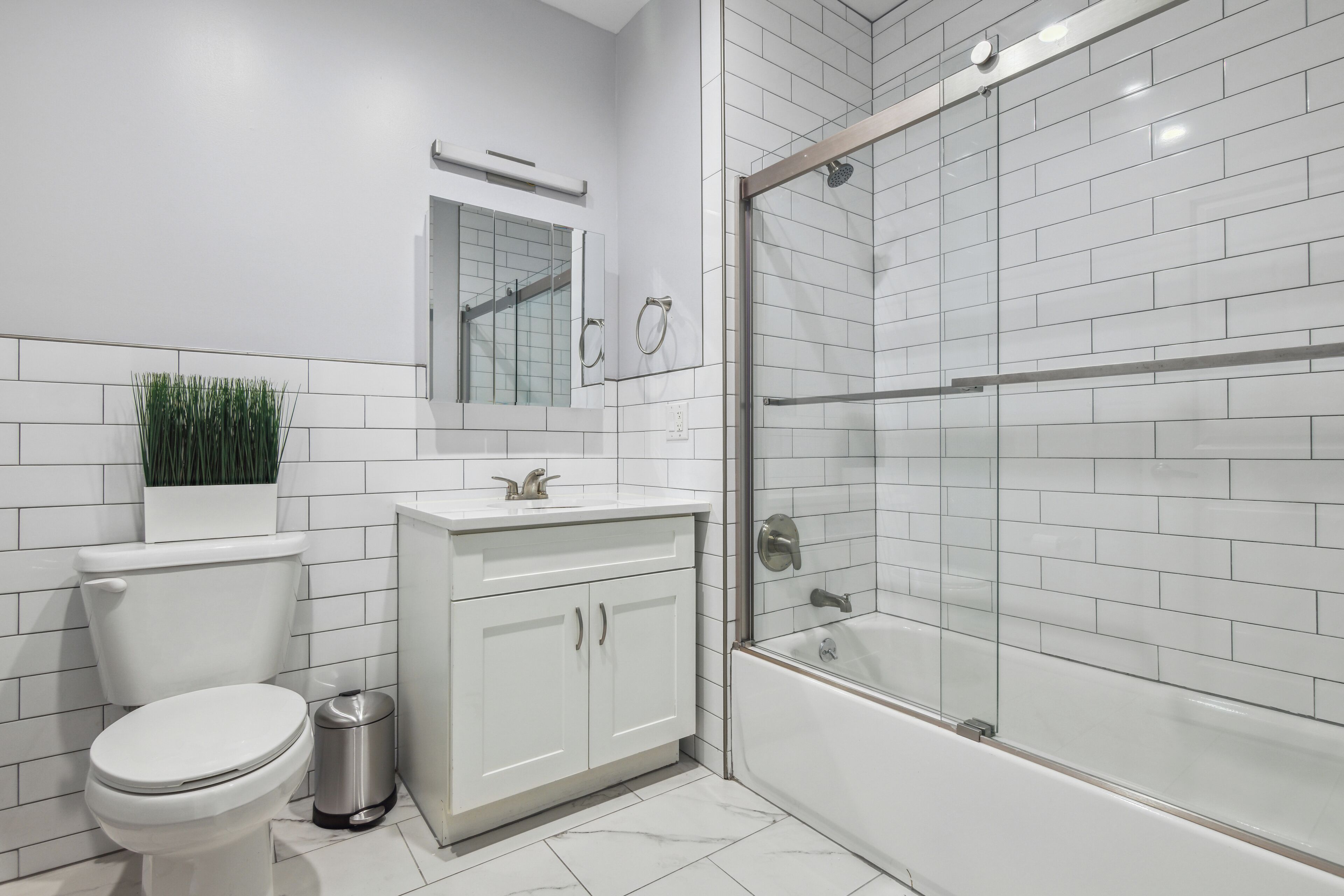 Un baño moderno con inodoro, lavamanos, tocador y ducha con mampara de vidrio.