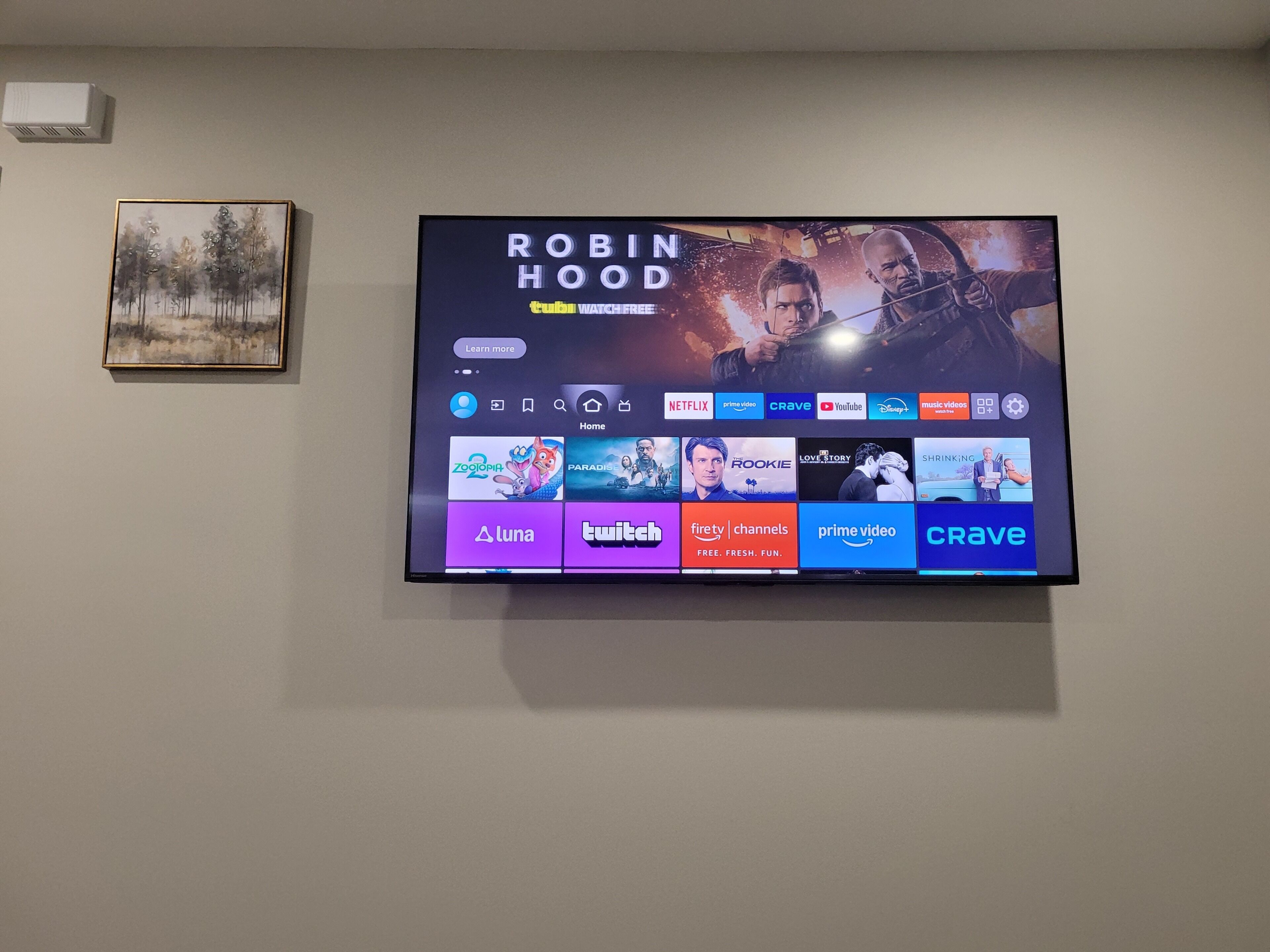 Ein Flachbildfernseher an der Wand, neben ihm ein 'Robin Hood' Filmplakat und ein gerahmtes Bild.