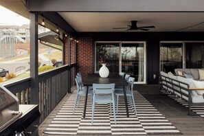 Une terrasse extérieure avec une table et des chaises, un grand vase et un ventilateur de plafond.