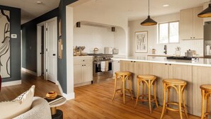 Una cocina moderna con una isla central, taburetes de bar y un comedor con mesa y sillas.