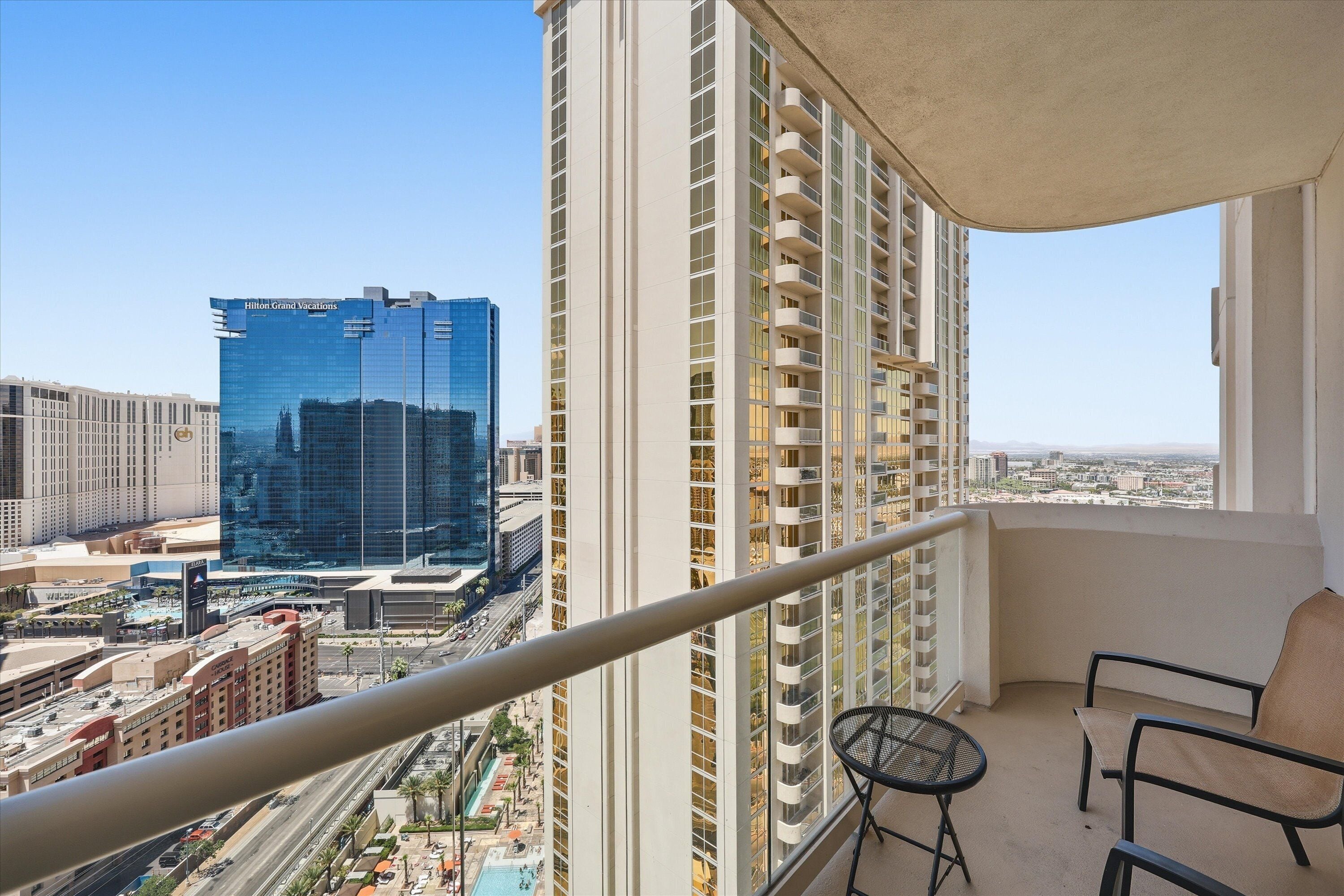 A balcony with a view of a cityscape, including a hotel and other buildings.