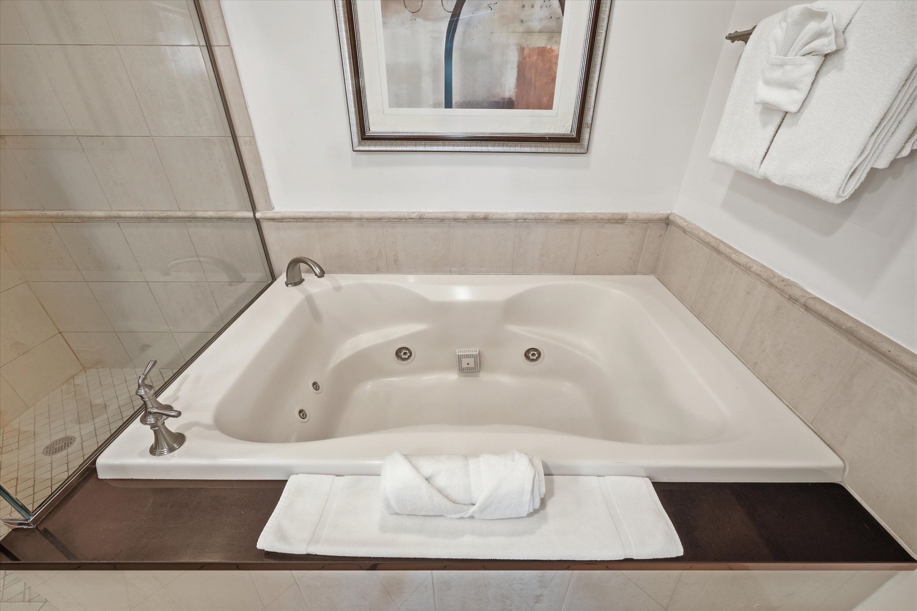 Une salle de bain moderne avec une baignoire sur pieds, un porte-serviettes et un miroir encadré.