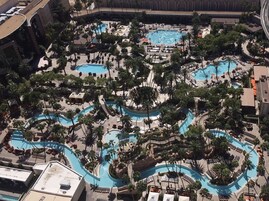 Vista aérea de um resort com várias piscinas, cercado por palmeiras e áreas de descanso.