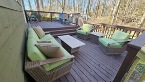 A wooden deck with wicker furniture, including a sofa and chairs, and a small table.