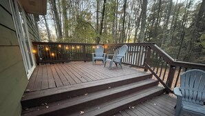 Eine Holzterrasse mit Stufen, die zu einem Sitzbereich mit zwei Stühlen und einem Tisch führen.