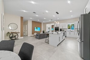 A modern kitchen with white cabinets, a central island, and stainless steel appliances.