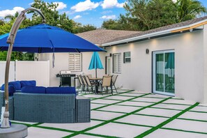 Une terrasse avec un barbecue, du mobilier d’extérieur et un espace salon abrité.