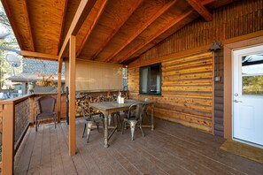 A wooden deck with a table and chairs, a door, and a window. - Cozy Cabin in the Pines w/ Grill & Outdoor Dining (Flagstaff)