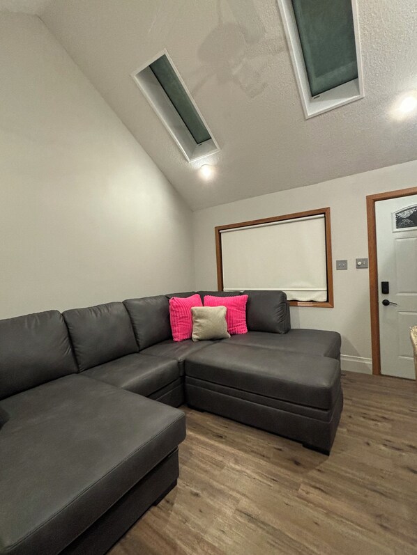 Un salon moderne avec un canapé d’angle, une lucarne et une porte.