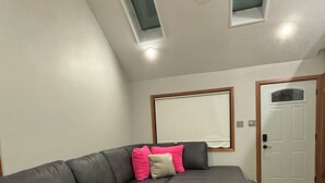 Een moderne woonkamer met een hoekbank, een houten vloer en dakramen.