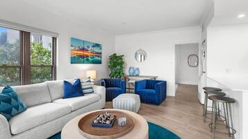 A modern living room with a sofa, armchairs, a coffee table, and a dining area with a plant and two vases.