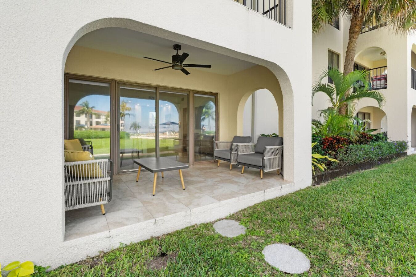 A covered outdoor seating area with a ceiling fan, two chairs, and a small table.