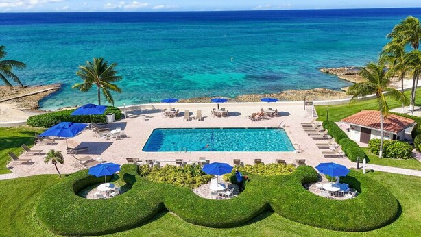 Un resort con piscina, sillones de descanso y sombrillas.