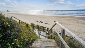 Una escalera de madera que conduce a una playa arenosa con vista al océano.