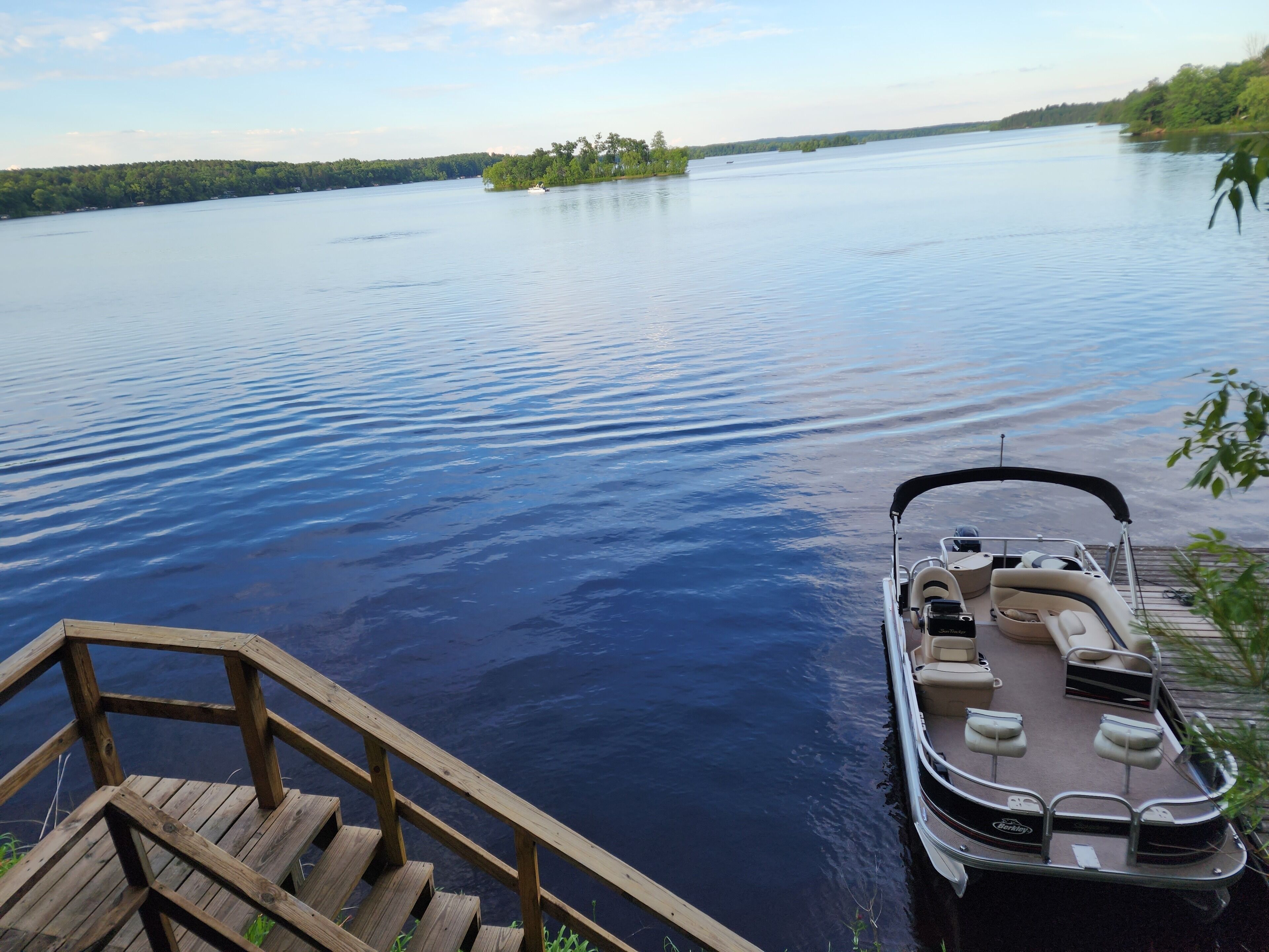 Un bateau était amarré à une jetée en bois, d’où l’on pouvait admirer un lac paisible et une île lointaine.