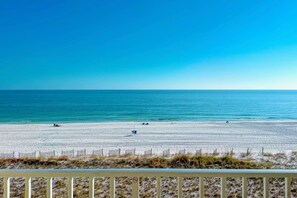 A beach with a clear sky, sandy shore, and a fence in the foreground. - Seacrest 407 | Sunny condo, gorgeous and quiet beach, great location! (Gulf Shores)