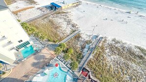 Vista aérea de un complejo turístico con piscina, acceso a la playa y puesto de salvavidas.