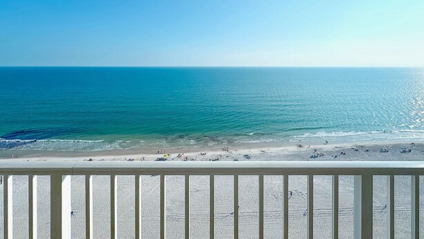 Une vue sur la plage avec une balustrade blanche au premier plan.