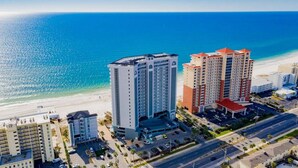Un hôtel situé sur la côte, composé de plusieurs immeubles de grande hauteur, avec un parking et une plage en arrière-plan.