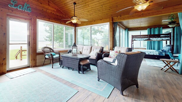 A cozy room with wicker furniture, a ceiling fan, and large windows. - Waterfront Home on Lake Limestone w/ Dock (Groesbeck)