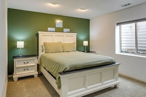 Quarto com cama, mesas de cabeceira, janela e parede verde.
