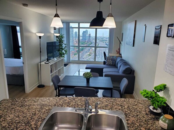 A modern kitchen with granite countertops, a double sink, and a dining area with a table and chairs.