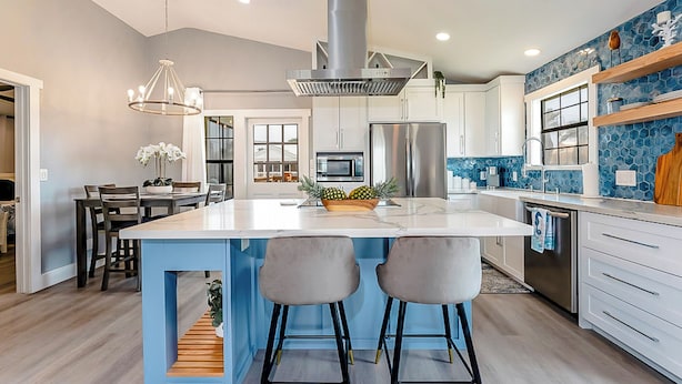 A modern kitchen with a large island, stainless steel appliances, and a blue accent wall. - Walk to Beach! Updated Home in South Padre Island (South Padre Island)