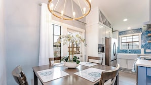 A modern kitchen with white cabinets, a stainless steel refrigerator, and a blue backsplash. - Walk to Beach! Updated Home in South Padre Island (South Padre Island)