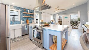 A modern kitchen with stainless steel appliances, a central island, and blue accent walls. - Walk to Beach! Updated Home in South Padre Island (South Padre Island)